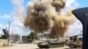 A smoke plume rises from an airstrike behind a tank belonging to forces loyal to Libya's Government of National Accord during clashes in the suburb of Wadi Rabie, south of the capital, Tripoli, April 12, 2019.