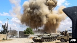 A smoke plume rises from an airstrike behind a tank belonging to forces loyal to Libya's Government of National Accord during clashes in the suburb of Wadi Rabie, south of the capital, Tripoli, April 12, 2019.