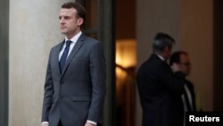 French President Emmanuel Macron accompanies a guest after a meeting at the Elysee Palace in Paris, Jan. 12, 2018.