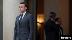 French President Emmanuel Macron accompanies a guest after a meeting at the Elysee Palace in Paris, Jan. 12, 2018.