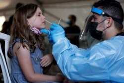 FILE - A health care worker tests a young person for COVID-19 at a temporary testing center, at Rabin Square in Tel Aviv, Israel, July 8, 2021.