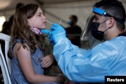 FILE - A health care worker tests a young person for COVID-19 at a temporary testing center, at Rabin Square in Tel Aviv, Israel, July 8, 2021.