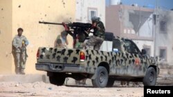 FILE - A member of Libyan forces allied with the U.N.-backed government fires a weapon on a pickup truck during a battle with Islamic State militants in Giza Bahreya, in Sirte, Libya, Oct. 27, 2016. 
