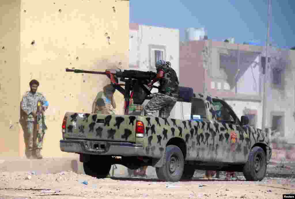 A member of Libyan forces allied with the U.N.-backed government fires a weapon on a pickup truck during a battle with Islamic State militants in Giza Bahreya, in Sirte, Libya.