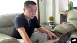 FILE - Veteran rights activist Huang Qi works on his laptop in his home in Chengdu in southwestern China's Sichuan province, Sept. 18, 2012.