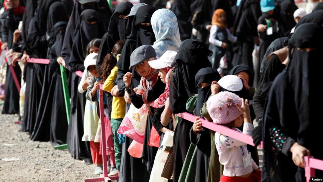 Perempuan dan anak-anak berbaris untuk memperoleh makanan berbuka puasa yang dibagikan oleh badan amal setempat selama bulan Ramadan di Sana'a, Yaman (12/6). 