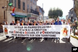Local residents hold a banner reading: " City of Pierrefeu says no to the creation of a reception center for migrants" during a march in Pierrefeu, southeastern France, Oct. 8, 2016.
