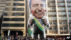 FILE - Supporters of presidential front-runner Jair Bolsonaro exhibit a large, inflatable doll in his image as they march along Paulista Avenue in Sao Paulo, Brazil, Sept. 9, 2018.