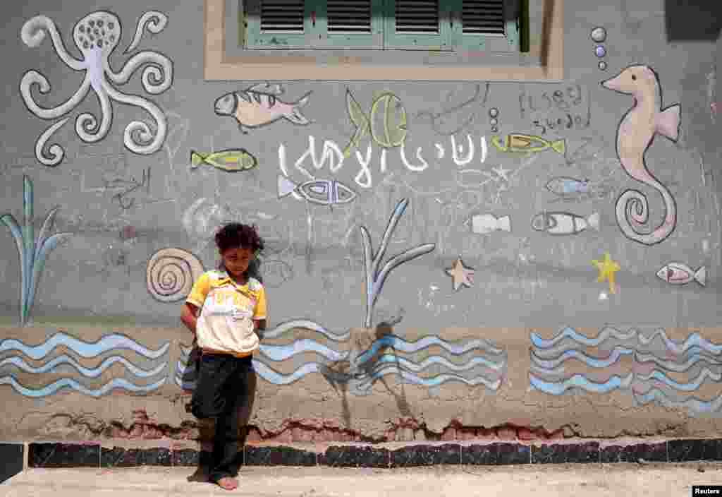 이집트&nbsp;카프르엘셰이크 주 엘 샤클루바에서 어린 소년이 그림이 그려진 자신의 집 벽 앞에 서 있다.