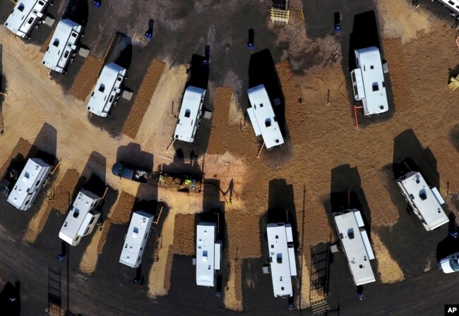 A worker sprays straw around newly setup Federal Emergency Management Agency trailers for residents left homeless by Hurricane Michael in Panama City, Fla, Thursday, Jan. 24, 2019.