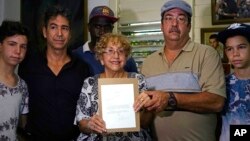 leana Yarza, de 76 años, rodeada de su familia, sonríe sosteniendo una copia impresa de una carta que el presidente Barack Obama le envió en el primer vuelo postal directo entre Estados Unidos y Cuba.