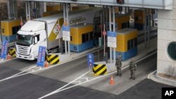 A South Korean truck heads to the North Korean city of Kaesong as South Korean Army soldiers stand guard at the customs, immigration and quarantine office near the border village of Panmunjom, in South Korea, Thursday, Feb. 11, 2016.