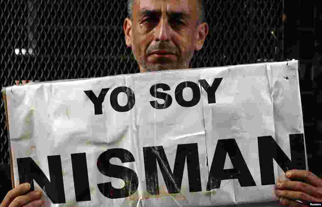 Ông Marcelo Novillo, có con trai là nạn nhân của một tội ác bạo lực, khóc khi cầm biểu ngữ với dòng chữ &quot;Tôi là Nisman&quot; bên ngoài văn phòng công tố đang điều tra cái chết của công tố viên Alberto Nisman ở Buenos Aires, Argentina. Công tố viên Alberto Nisman, người cáo buộc Tổng thống Argentina tìm cách để làm chệch hướng cuộc điều tra về một vụ đánh bom năm 1994, đã chết một cách bí ẩn vào ngày 18 tháng 1, 2015.