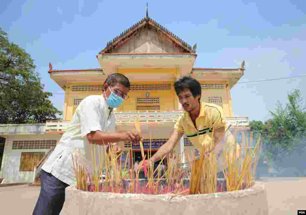 Two men light incense at Niroth Rangsey pagoda during the Khmer New Year, Phnom Penh, Cambodia, April 14, 2020. (Kann Vicheika/VOA Khmer)