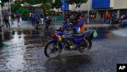 Un hombre en moto cruza un charco en Caracas, Venezuela, el 29 de junio de 2022. 