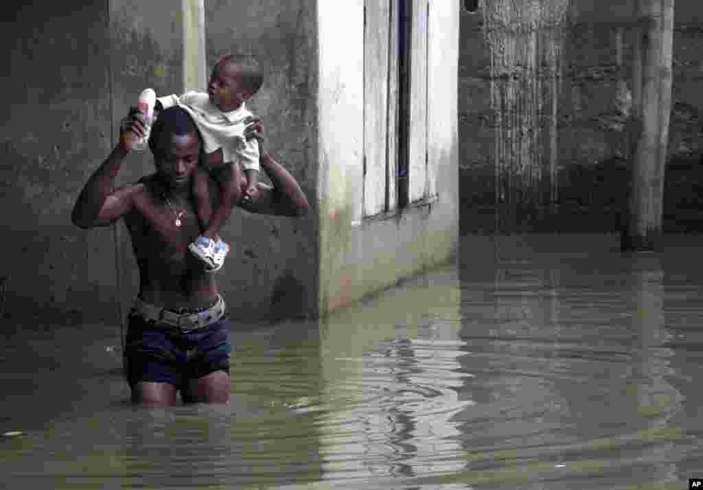A man carries a child as he wades through flood waters in Ikorodu neighbourhood of Nigeria's main city of Lagos, August 5, 2007. Flash floods sweeping Nigeria's biggest city, Lagos, have forced thousands of families from their homes, residents and witness