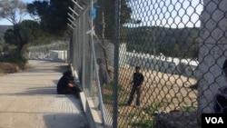 Along the chain-link fence at the camp in Lesbos, Greece, an occasional aid worker, local resident or journalist stops to talk to refugees inside, who are eager for any news, April 1, 2016. (H. Murdock/VOA)