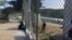 Along the chain-link fence at the camp in Lesbos, Greece, an occasional aid worker, local resident or journalist stops to talk to refugees inside, who are eager for any news, April 1, 2016. (H. Murdock/VOA)