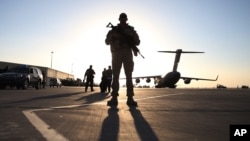 FILE - A solider stands guard near a military aircraft in Kandahar, Afghanistan.