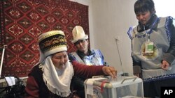 Election commission officials wait as an elderly Kyrgyz woman, left, casts her ballot at home in the village of Kizil Birlik, 25 km (14 miles) south of Bishkek, Kyrgyzstan, October 29, 2011.
