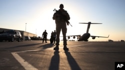 FILE - A solider stands guard near a military aircraft in Kandahar, Afghanistan.