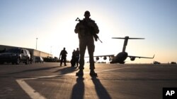 FILE - A solider stands guard near a military aircraft in Kandahar, Afghanistan.