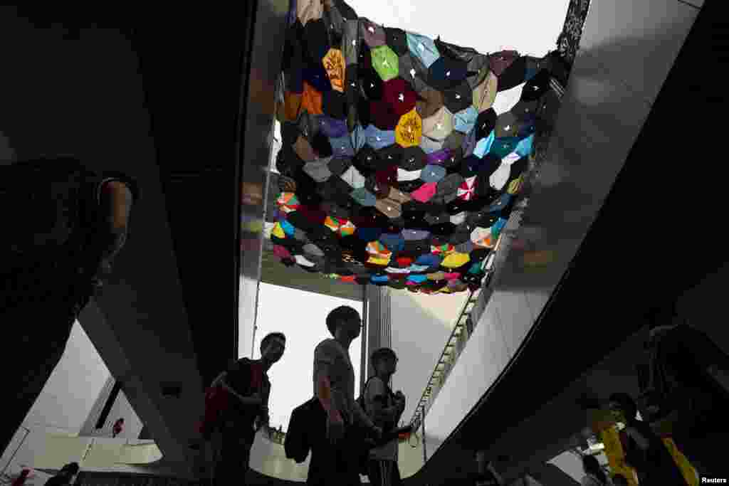 Protesters walk under an art installation made from umbrellas by a local artist outside the government headquarters in Hong Kong, Oct. 3, 2014. 