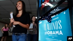 FILE - Two volunteers for President Barack Obama's campaign, Carissa Valdez, right, and Vanessa Trujillo, leave campaign headquarters as they work to register new voters while they canvass a heavily Latino neighborhood shopping plaza in Phoenix, June 29, 2012.