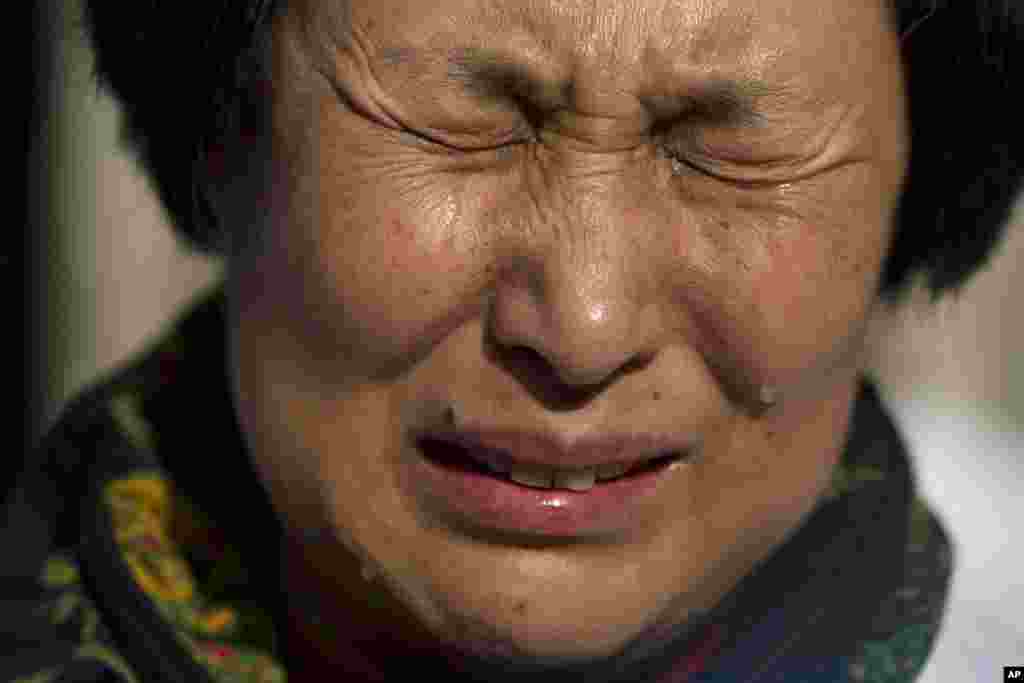 Liu Guiqiu, yang anak laki-lakinya adalah salah satu penumpang pesawat Malaysia Airlines penerbangan 370 yang hilang, menangis ketika berdemo di Kedutaan Malaysia di Beijing dalam peringatan satu tahun hilangnya pesawat tersebut.