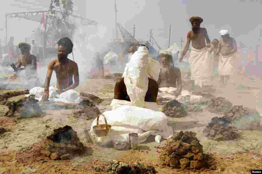 Sadhus, or Hindu holy men, perform prayers while sitting inside circles of burning &quot;Upale&quot; - dried cow dung cakes - on the banks of the Ganges River during the Magh Mela festival in the northern Indian city of Allahabad.