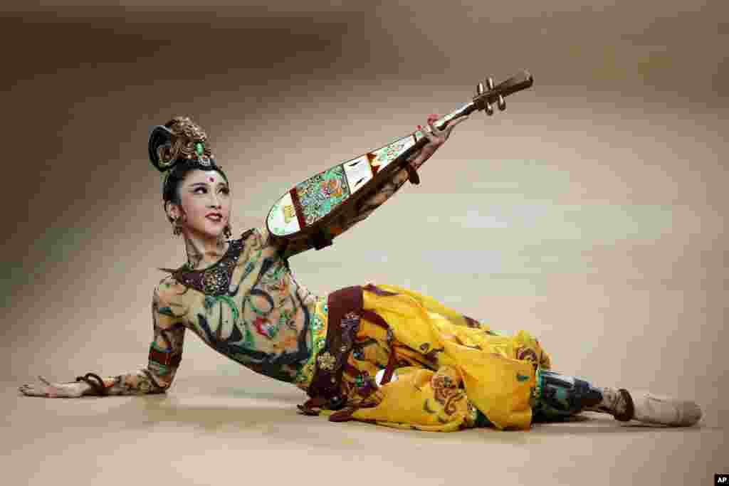 A dancer performs with a pipa, a Chinese traditional musical instrument on stage during the NE TIGER Haute Couture 2018 collection with &quot;The Road&quot; theme in the opening show for the China Fashion Week in Beijing.