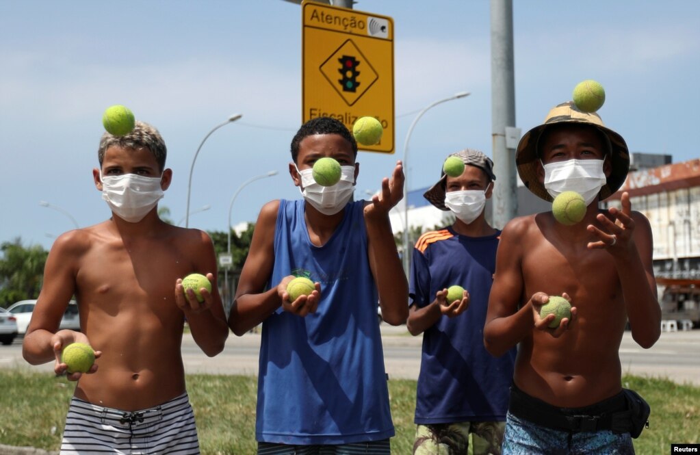 Unos jóvenes actúan con pelotas de tenis para recibir propinas mientras usan máscaras&nbsp; protectoras en la Avenida América, en Río de Janeiro, Brasil.&nbsp;