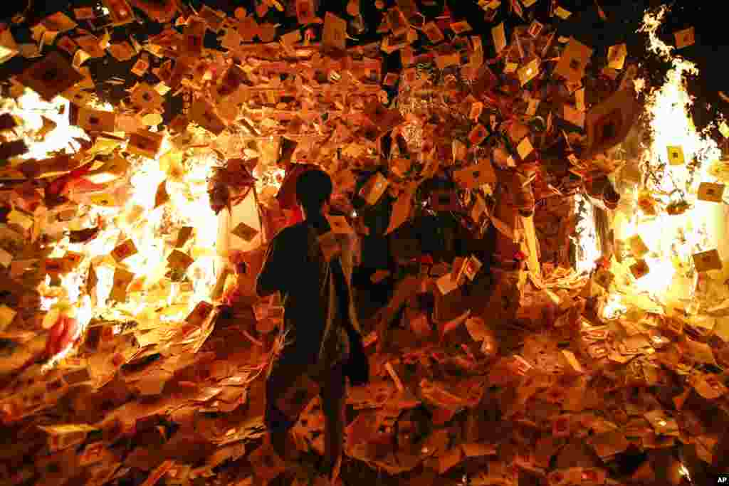 An ethnic Chinese man throws papers at a paper statue of Chinese deity known as "Da Shi Ye," or "Guardian God of Ghosts," during the Ghost festival in Kajang, outside Kuala Lumpur, Malaysia.