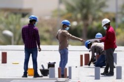 FILE - Workers wearing protective face masks work on a construction site in Dubai, United Arab Emirates, April 14, 2020.