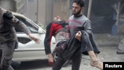 A resident carries an injured man through a site damaged from what activists said was an airstrike by forces loyal to Syria's President Bashar al-Assad on the main field hospital in the town of Douma, Syria, Oct. 29, 2015.