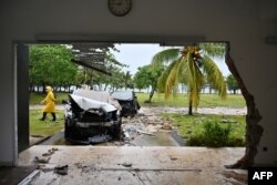 Seorang petugas keamanan berjalan melewati mobil-mobil yang rusak diterjang tsunami di kawasan wisata Tanjung Lesung, Banten, Rabu, 26 Desember 2018. (Foto: AFP)