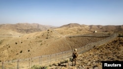 FILE - A soldier stands guard along the border fence outside the Kitton outpost on the border with Afghanistan in North Waziristan, Pakistan Oct. 18, 2017.