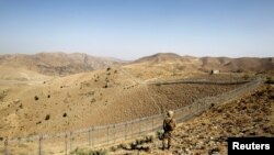 FILE - A Pakistani soldier stands guard along the border fence outside the Kitton outpost on the border with Afghanistan in North Waziristan, Pakistan Oct. 18, 2017.