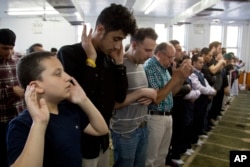 Men and children attend a prayer service at Masjid Al-Farooq for the Muslim holiday of Eid al-Fitr, June 15, 2018, in the Brooklyn borough of New York.