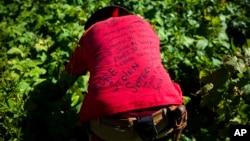 FILE - Randy Ortiz wears a shirt with the names of missing and murdered indigenous women as he searches for Ashley HeavyRunner Loring in the mountains of the Blackfeet Indian Reservation in Babb, Mont., July 12, 2018. On some reservations, Native American women are murdered at a rate more than 10 times the national average, and a third of all Native American women will be raped at some point, according to the Justice Department.