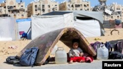 A displaced Palestinian girl sits under a mattress as waits to flee Hamad City with her family following an Israeli evacuation order, in Khan Younis in the southern Gaza Strip, Aug. 11, 2024. 