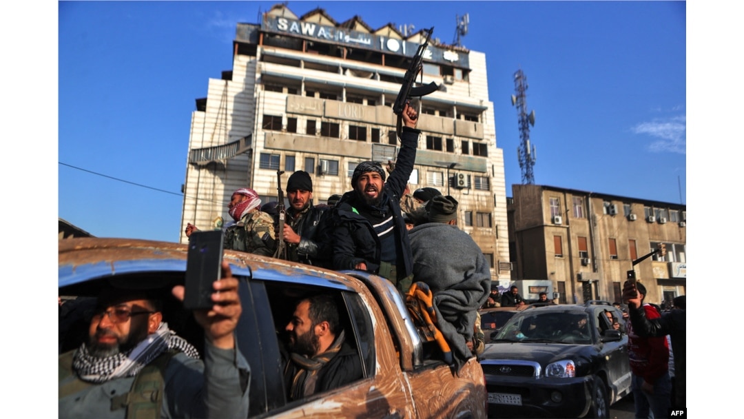 Pemberontak Suriah merayakan kemenangan di sekitar Menara Jam di Homs pada 8 Desember 2024, setelah berhasil memasuki kota terbesar ketiga di Suriah pada malam sebelumnya. (Foto: AFP)