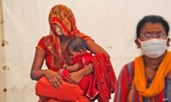 Dos mujeres esperan recibir la vacuna contra el COVID-19 en Nueva Delhi, India, el 2 de julio de 2021.