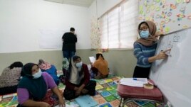 A volunteer teacher, right, gives a basic English lesson to a minority Muslim Rohingya refugees at a slum on the outskirts of Kuala Lumpur, Malaysia, on Oct. 11, 2020.