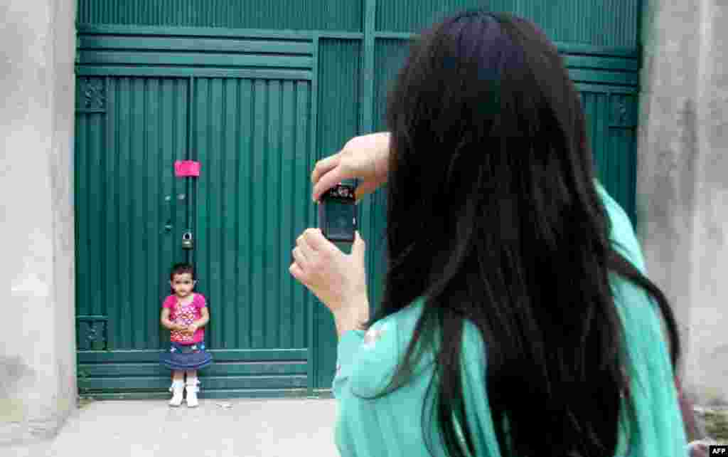 May 5: A woman photographs her daughter at a gate of the compound where Osama bin Laden was caught and killed in Abbottabad, Pakistan. (AP Photo/Aqeel Ahmed)