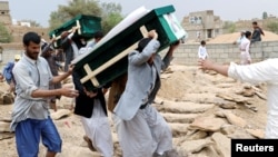 Mourners carry coffins during a funeral of the people, mainly children, killed in a Saudi-led coalition airstrike on a bus in northern Yemen, in Saada, Yemen, Aug. 13, 2018. 