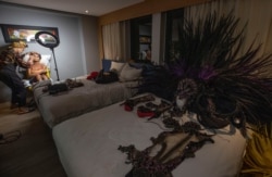 Camila Prins sits in a chair as she has her makeup done before performing for Colorado do Bras samba school in Sao Paulo, Brazil, Feb. 22, 2020. Her costume is ready on a nearby bed.