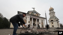 FILE - A man clears the rubble in front of St. Andrew's Cathedral which was damaged by a Russian strike on Zaporizhzhia, Ukraine, Jan 18, 2025.