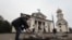 FILE - A man clears rubble in front of St. Andrew's Cathedral, which was damaged by a Russian strike on Zaporizhzhia, Ukraine, Jan. 18, 2025.
