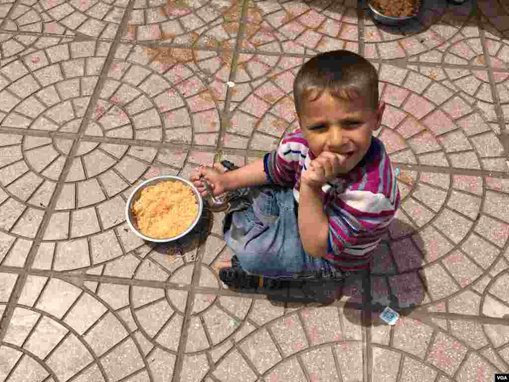 Young Iraqi boy eating rice with tomato sauce and potatoes supplied in a Kurdish-run camp for Iraqis fleeing IS, April 11, 2016. (S. Behn/VOA)